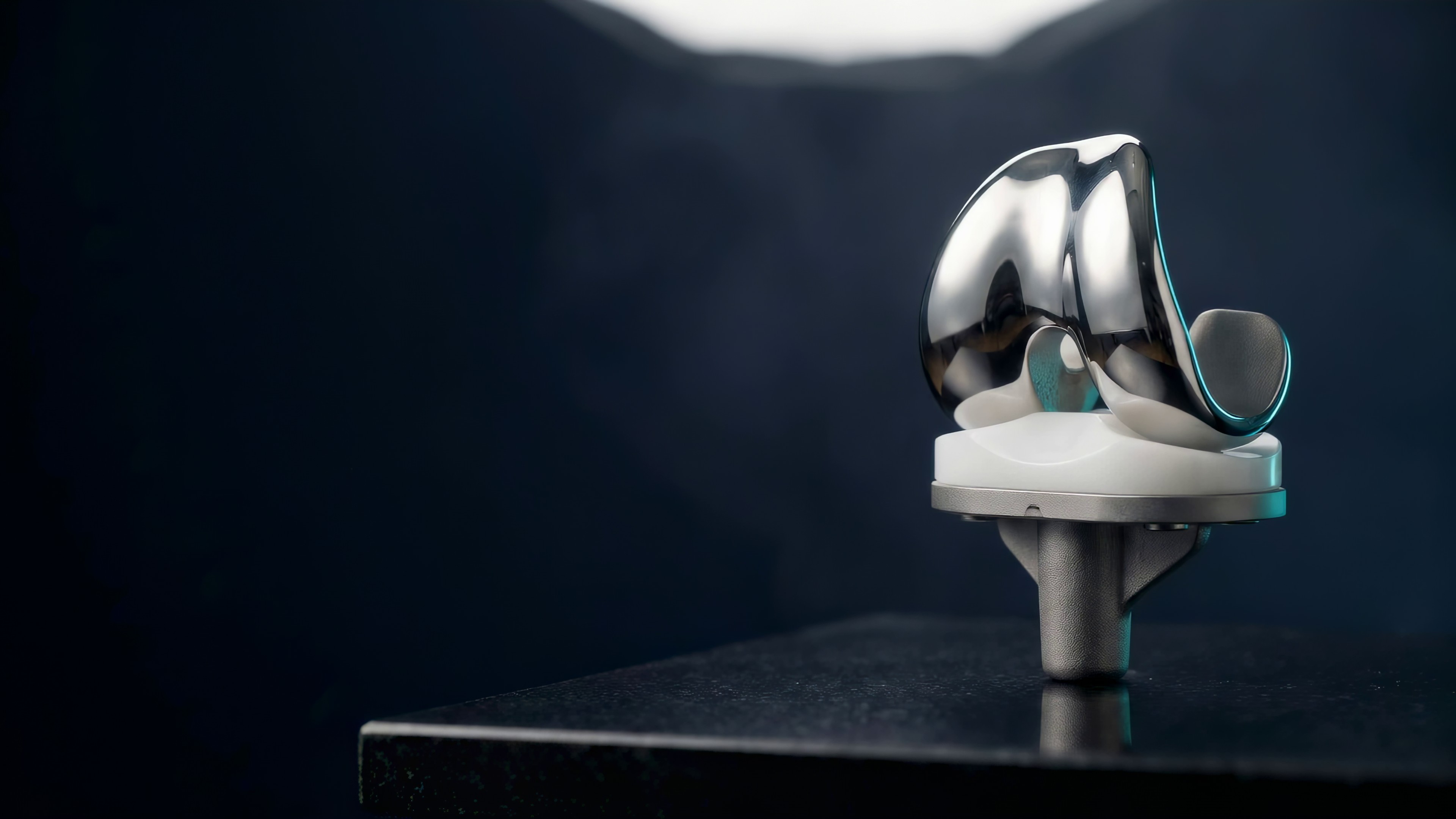 A close detail of a knee implant, lit against a dark background